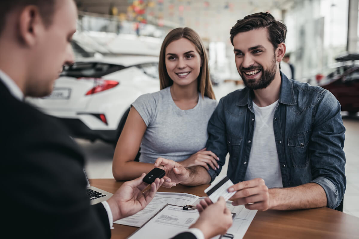 couple filling out finance paperwork at car dealership couple filling out finance paperwork at car dealership